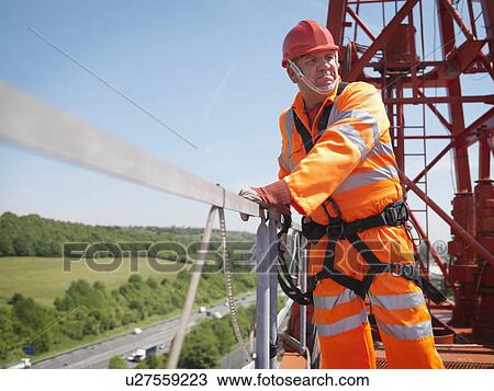 Stock Image - Crane Worker With Harness On Crane. Fotosearch