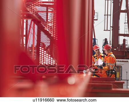 Stock Image - Crane Workers Discussing Notes. Fotosearch