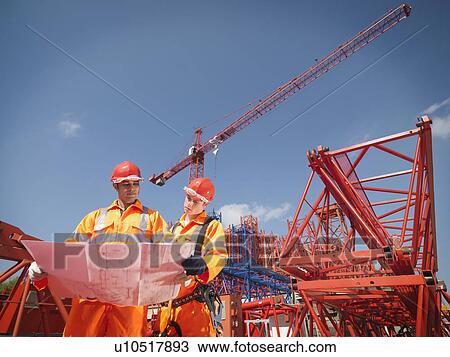 Stock Image - Crane Workers Looking At Plans. Fotosearch