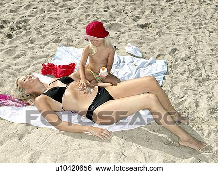 Stock Photograph - Daughter putting sun block on mother. Fotosearch