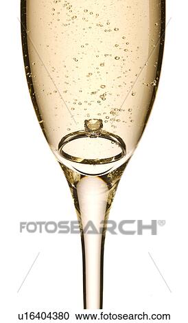 Stock Image - Engagement ring in glass of champagne. Fotosearch