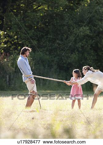 Stock Photo - Family playing with rope in field. Fotosearch