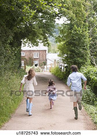 Stock Image - Family running towards country house. Fotosearch