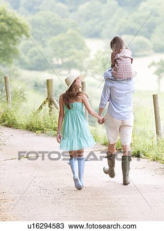 Stock Image - Family walking together on lane. Fotosearch