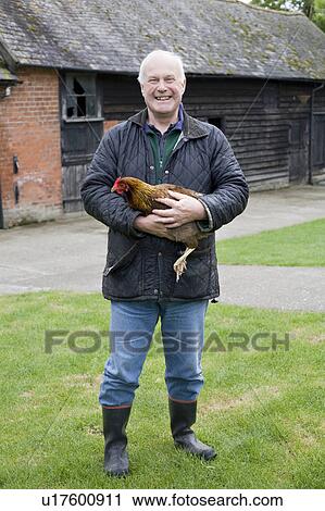 Stock Image - Farmer holding chicken. Fotosearch