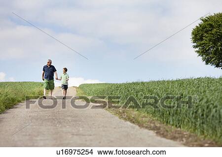 Picture - Father and son walking down a road. Fotosearch
