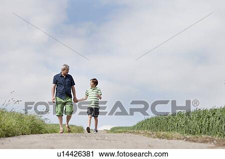 Stock Image - Father and son walking down a road. Fotosearch