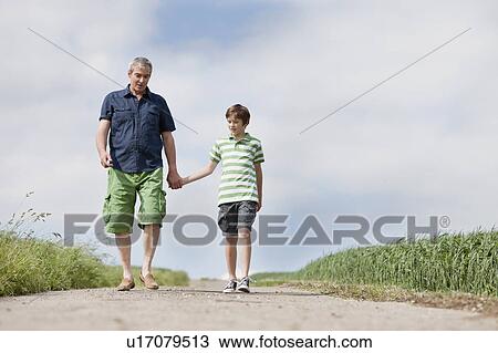 Stock Image - Father and son walking down a road. Fotosearch