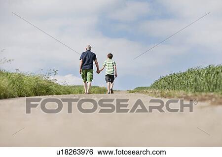 Stock Photograph - Father and son walking up a road. Fotosearch