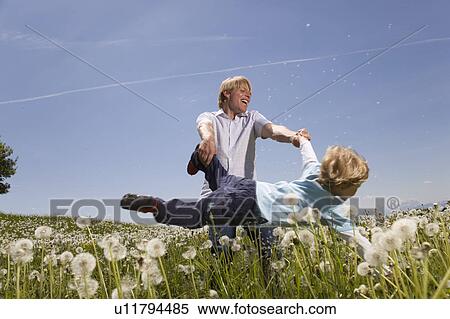 father swinging son in meadow View Large Photo Image Stock Photography - father swinging son in meadow. Fotosearch