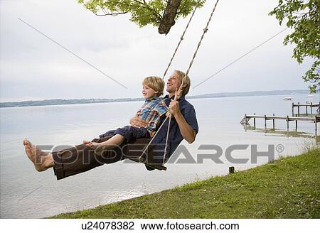 Stock Image - father with son on swing. Fotosearch