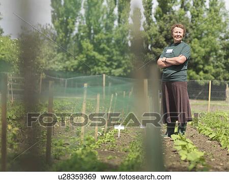Stock Photo - Female Garden Worker In Rows Of Plants. Fotosearch