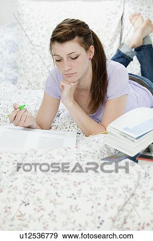 Female student lying in bed, learning View Large Photo Image Stock Photo - Female student lying in bed, learning. Fotosearch