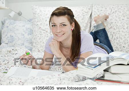 Stock Photography - Female student lying in bed, learning. Fotosearch