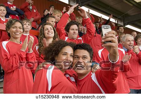 Stock Photo - Football fans photographing themselves. Fotosearch