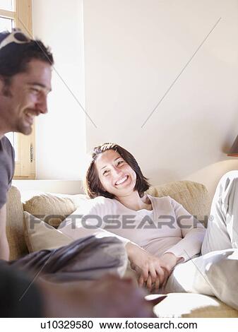 Stock Image - friends laughing in chalet living room. Fotosearch