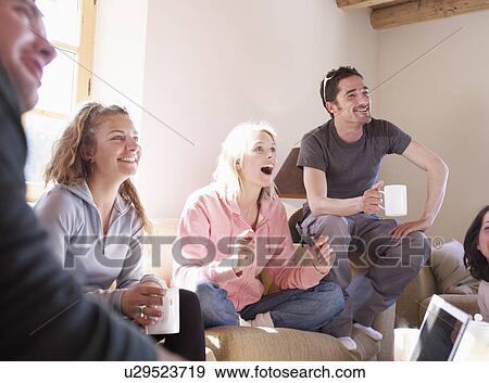 Stock Photo - friends laughing in chalet living room. Fotosearch