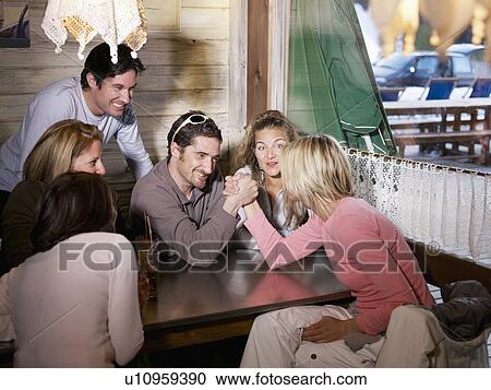Stock Image - friends laughing in ski lodge bar. Fotosearch