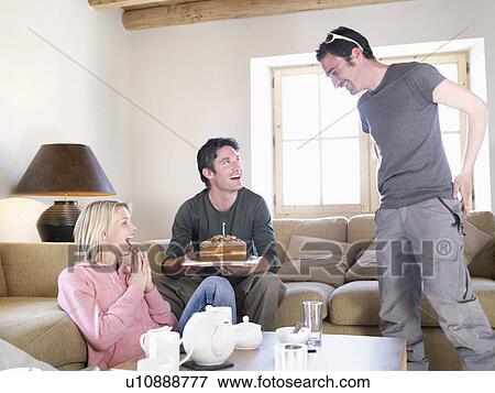 Stock Photo - friends laughing with cake in chalet. Fotosearch
