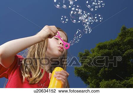 Stock Image - Girl blowing bubbles. Fotosearch