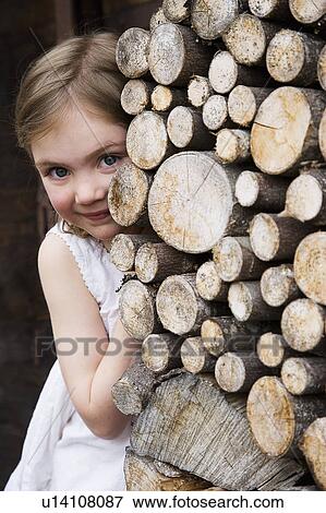 Stock Photo - Girl hiding behind logs.. Fotosearch
