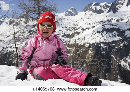 Stock Photo - Girl in pink sitting in the snow.. Fotosearch