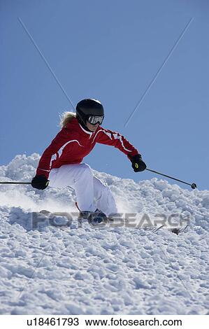 Stock Image - Girl in red carving off piste.. Fotosearch