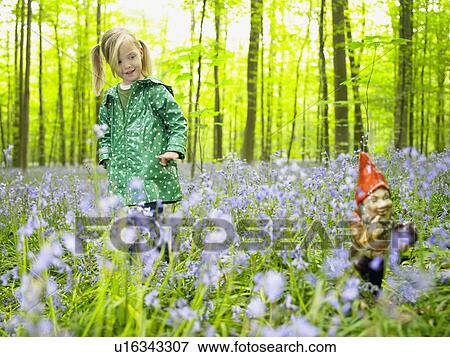 Girl looking at a garden gnome View Large Photo Image Stock Photo - Girl looking at a garden gnome. Fotosearch