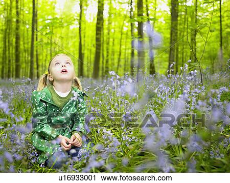 Stock Image - Girl looking up, in the woods. Fotosearch