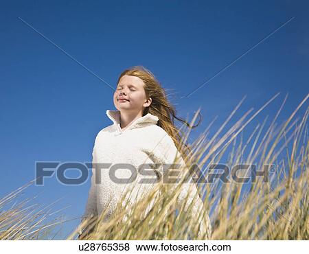 Stock Photo - Girl on dunes against blue sky. Fotosearch