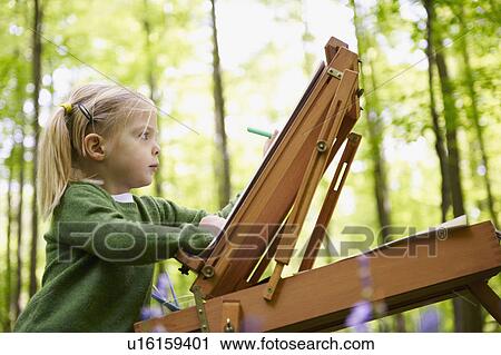 Stock Image - Girl painting in the forest. Fotosearch
