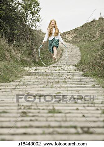 Stock Image - Girl skipping towards camera. Fotosearch