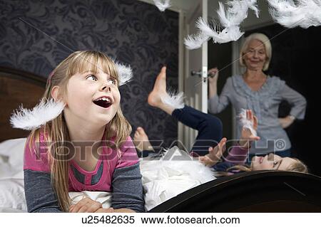 Stock Photography - Girl watches feathers after pillow fight. Fotosearch