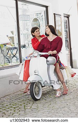 Stock Image - girlfriends on a motor scooter. Fotosearch