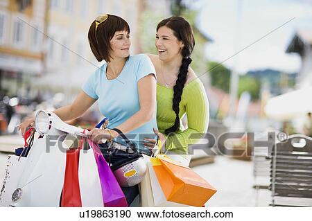Stock Image - girlfriends with motor scooter. Fotosearch
