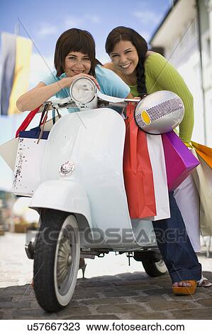 Stock Image - girlfriends with motor scooter. Fotosearch
