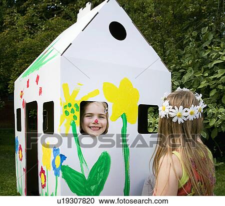 Stock Image - Girls play with a cardboard wendy house. Fotosearch