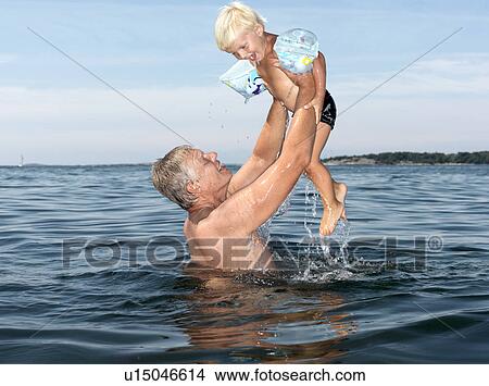 Picture - Grandfather and boy playing in water. Fotosearch