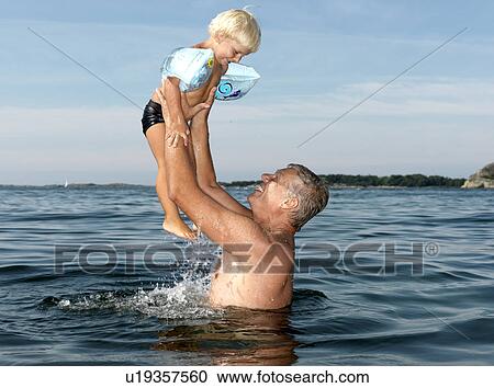 Grandfather playing with boy in water View Large Photo Image Stock Image - Grandfather playing with boy in water. Fotosearch
