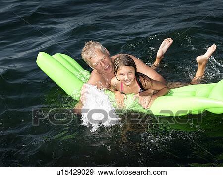 Grandfather playing with girl in water View Large Photo Image Stock Photo - Grandfather playing with girl in water. Fotosearch
