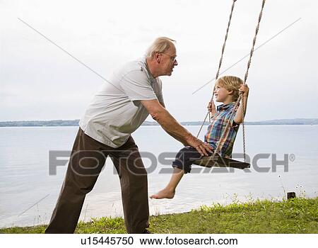 Stock Image - grandfather with grandson on swing. Fotosearch