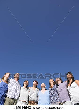 Stock Image - group of young people looking at sun. Fotosearch