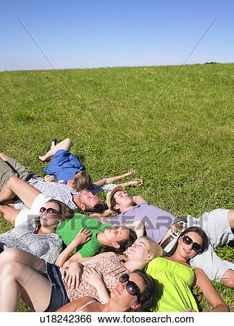 Stock Photograph - group of young people lying in field. Fotosearch