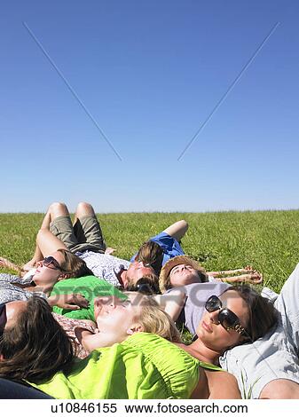 Stock Photography - group of young people lying in field. Fotosearch