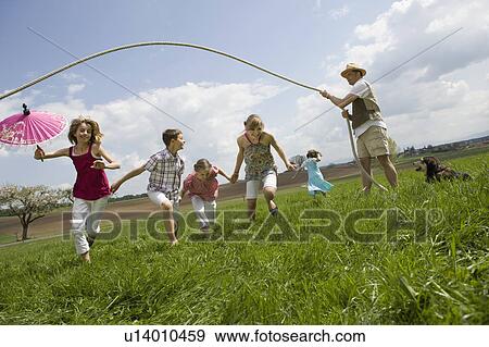 Stock Photo - Happy family jump roping in countryside. Fotosearch