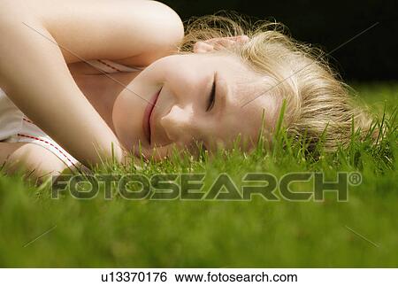 Stock Photograph - Head shot of a girl lying on a lawn. Fotosearch