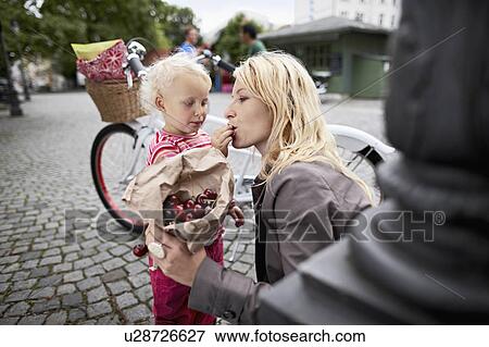 Little girl and mother eating cherries View Large Photo Image Stock Photo - Little girl and mother eating cherries. Fotosearch