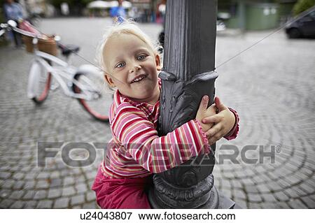 Stock Photo - Little girl climbing up a lantern. Fotosearch
