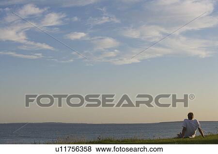 Male sitting on the grass View Large Photo Image Stock Photo - Male sitting on the grass. Fotosearch