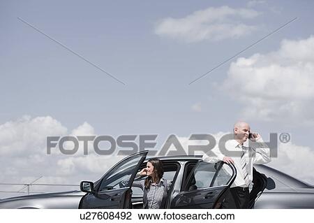 Stock Image - man and woman near car on the phone. Fotosearch
